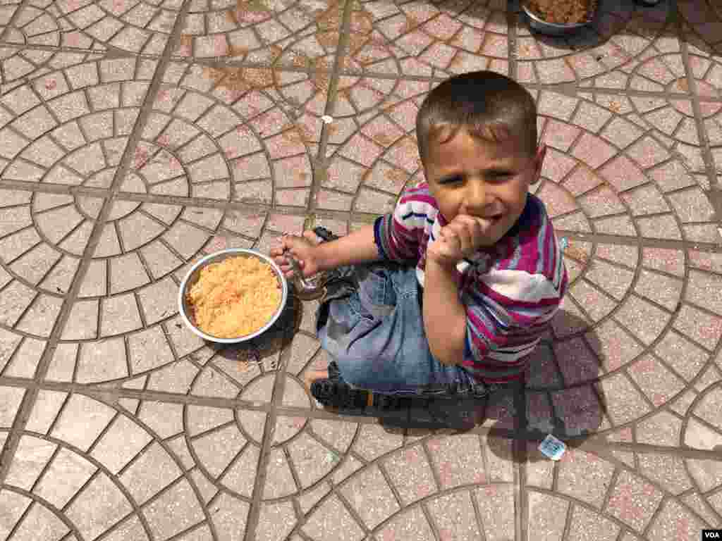 Seorang anak pengungsi makan nasi dengan saus tomat dan kentang yang disediakan di kamp pengungsi untuk warga Irak yang melarikan diri dari kelompok Negara Islam (ISIS) (11/4). (VOA/S. Behn)