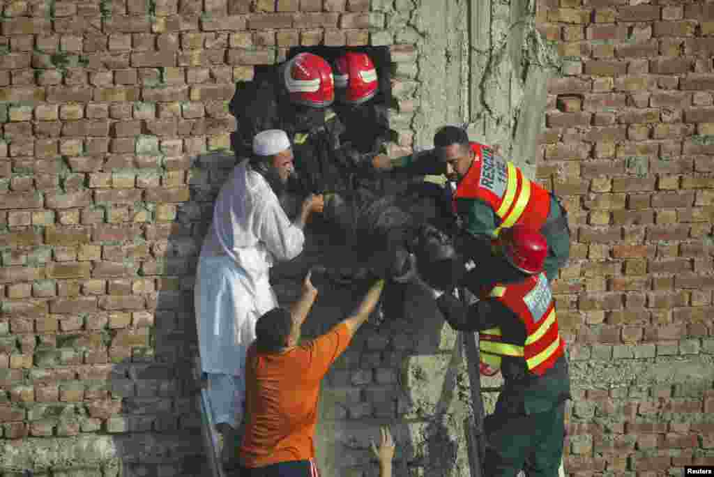 Rescue workers and residents recover a body from a building after a fire at a shoe factory in Lahore, September 11, 2012.