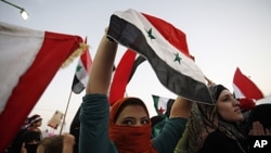 Syrian women hold the national flag and protest in front of the Syrian embassy condemning the killing and torturing women in Syria by Bashar al-Assad's regime, in Amman, Jordan, September 29, 2011.