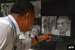 FILE - A man looks at a portrait of former head of the Tuol Sleng prison Kaing Guek Eav, also known as Duch, at the Tuol Sleng genocide museum in Phnom Penh on September 2, 2020.