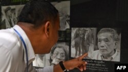 A man looks at a portrait of former head of the Tuol Sleng prison Kaing Guek Eav, also known as Duch, at the Tuol Sleng genocide museum in Phnom Penh on September 2, 2020. (Photo by TANG CHHIN Sothy / AFP)