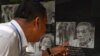 A man looks at a portrait of former head of the Tuol Sleng prison Kaing Guek Eav, also known as Duch, at the Tuol Sleng genocide museum in Phnom Penh on September 2, 2020. (Photo by TANG CHHIN Sothy / AFP)