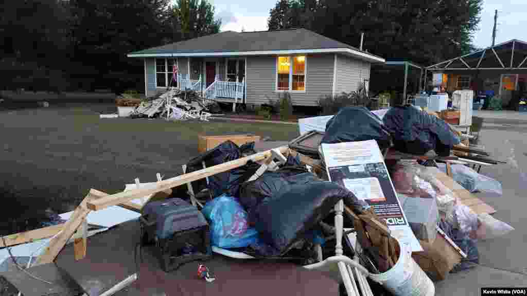 Warga St. Amant, Louisiana, mengeluarkan barang-barang yang rusak karena banjir dari rumah mereka (22/8).