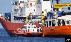An Italian Coast Guard boat approaches the French NGO "SOS Mediterranee" Aquarius ship as migrants are being transferred, in the Mediterranean Sea, June 12, 2018.