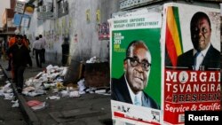 Election campaign posters are pictured near Zimbabweans walking on a street blocked by uncollected garbage in Harare, July 17, 2013. 
