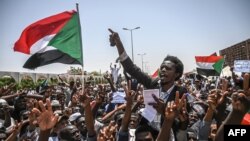 Sudanese protesters wave national flags as they chant slogans during a sit-in outside the army headquarters in the capital Khartoum, April 26, 2019.