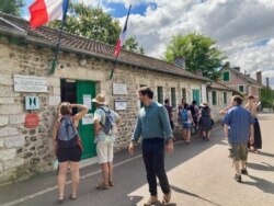 Tourists check out opening hours at Claude Monet's house, which reopened in June following France's two-month coronavirus lockdown. (Photo: Lisa Bryant/VOA)