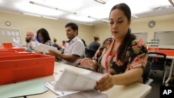 FILE -Bianca Savola, an election clerk at the Sacramento County Registrar of Voters, inspects mail-in ballots in Sacramento, Calif., May 30, 2018.