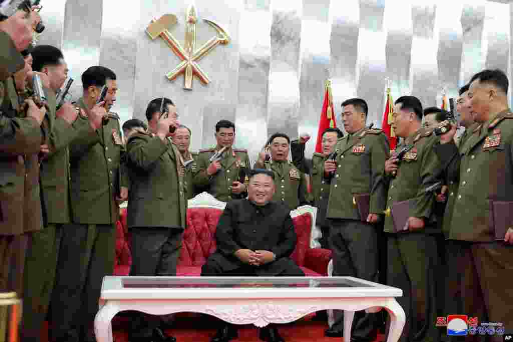 Pemimpin Korea Utara Kim Jong Un (duduk) dikelilingi oleh pejabat militer senior yang memegang pistol siap untuk menunggu perintahnya, selama upacara peringatan 67 Tahun Kemenangan dalam Perang Korea, di Pyongyang, 26 Juli 2020. (foto dirilis oleh KCNA)