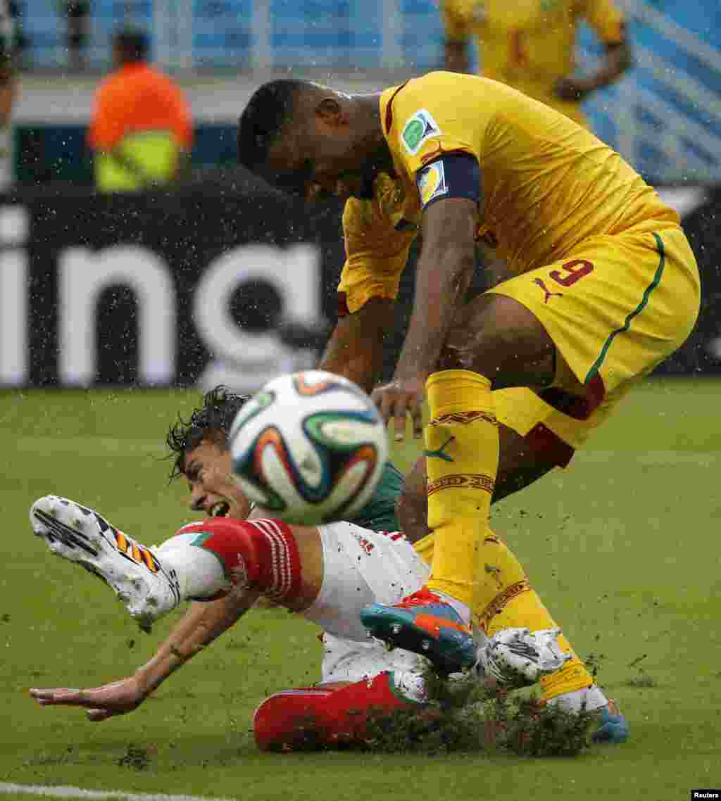 Hector Moreno dari Meksiko (bawah) berebut bola dengan Samuel Eto&#39;o dari Kamerun selama pertandingan Grup A di stadion Dunas di Natal (13/6). (Reuters/Jorge Silva)