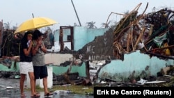 Women share an umbrella as they look at a house that was destroyed after Super Typhoon Haiyan hit Tacloban in central Philippines.