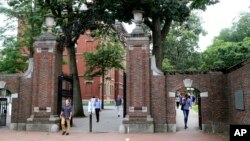 FILE - Para pejalan kaki melewati gerbang Harvard Yard di Universitas Harvard, Cambridge, Massachusetts.