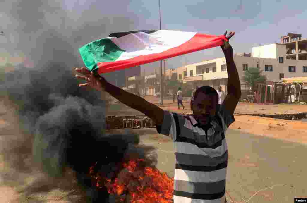 Um manifestante agita uma bandeira durante o que o Ministério da Informação chama de golpe militar em Cartum, Sudão, em 25 de Outubro de 2021. Os manifestantes estão há mais de uma semana na rua a protestar a atitude dos militares.