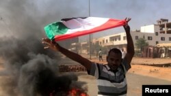 FILE - A protester waves a flag during what the information ministry calls a military coup in Khartoum, Sudan, Oct. 25, 2021. 