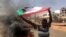 FILE - A protester waves a flag during what the information ministry calls a military coup in Khartoum, Sudan, Oct. 25, 2021. 