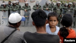 ဗင်နီဇွဲလား လုံခြုံရေးတပ်ဖွဲ့တွေနဲ့ မျက်နှာချင်းဆိုင်ရပ်ပြီး ဖြတ်ကျော်ဖို့ စောင့်ဆိုင်းနေသူများ။ (ဖေဖေါ်ဝါရီ ၂၂၊ ၂၀၁၉) 