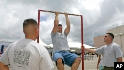 FILE - Matt Elam, center, competes in a US Marine pull-up contest while Marine recruiters watch.