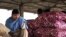 An Indian worker sits on sacks of onions at a wholesale market on the outskirts of Jammu, 22 Dec 2010