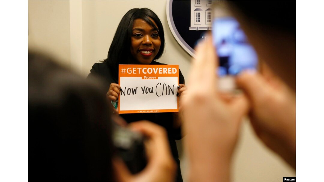 FILE - A woman poses for photos while holding a placard with her thoughts on health care at the White House Youth Summit on the Affordable Care Act in Washington, Dec. 4, 2013.