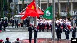 In this photo released by Xinhua News Agency, policemen perform a flag-raising ceremony in Macao, Dec. 20, 2021, marking the 22nd anniversary of the former Portuguese colony's handover to Chinese rule. 