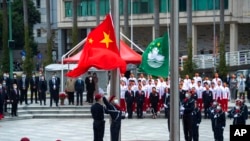 FILE - In this photo released by Xinhua News Agency, policemen perform a flag-raising ceremony in Macao, Dec. 20, 2021, marking the 22nd anniversary of the former Portuguese colony's handover to Chinese rule.