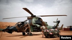 Des soldats français inspectent un hélicoptère d'attaque Tiger au camp opérationnel de la plateforme du désert (PfOD) lors de l'opération Barkhane à Gao, au Mali, le 1er août 2019.