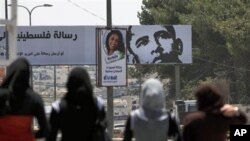 Palestinian girls walk near a billboard with a picture of US President Barack Obama, in the West Bank city of Ramallah.