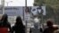 Palestinian girls walk near a billboard with a picture of US President Barack Obama, in the West Bank city of Ramallah.
