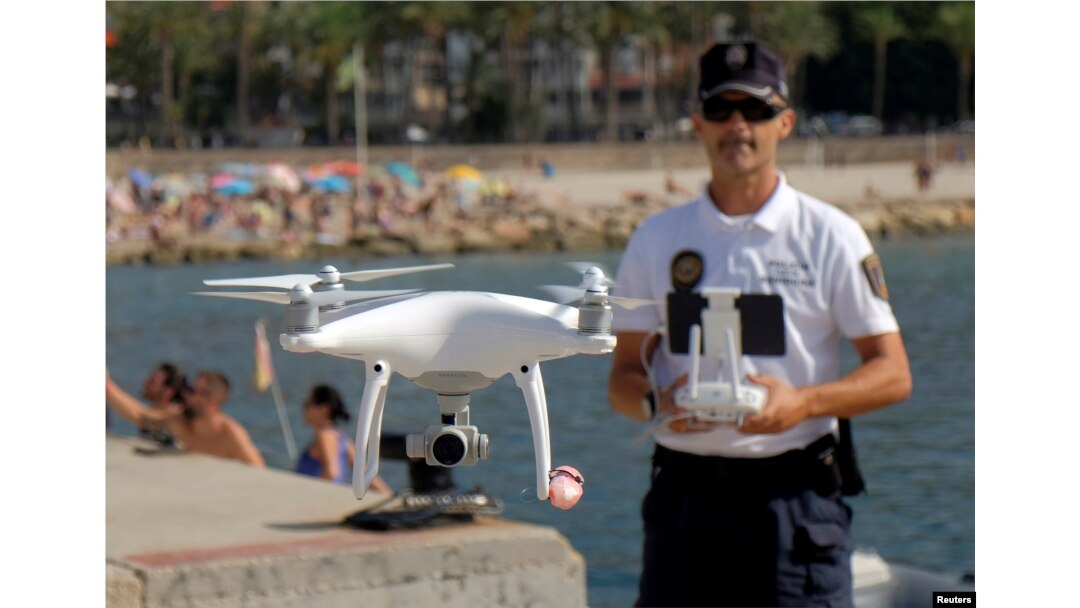 Local police officer Agustin Mirete controls a drone equipped with a camera used for surveillance tasks in the Poniente beach at the eastern costal town of Benidorm, Spain, Aug. 18, 2016.