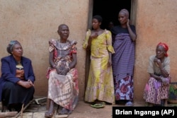 Prudencienne Namukobwa, 85, second left, sits with her guests outside her house in Ngozi, Burundi, Friday, Sept. 20, 2024. (AP Photo/Brian Inganga)