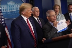 U.S. President Donald Trump listens as National Institute of Allergy and Infectious Diseases Director Anthony Fauci speaks while holding up a coronavirus chart reading "15 Ways to Slow the Spread," at the White House, March 20, 2020.