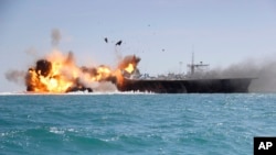 In this picture released by the Iranian Tasnim news agency on Feb. 25, 2015, a replica of a U.S. aircraft carrier is exploded by the Revolutionary Guard's speedboats during large-scale naval drills near the entrance of the Persian Gulf, Iran.