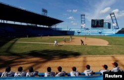 Japan's national youth baseball team players (back to camera) watch a friendly game against Cuba at the Latinoamericano stadium in Havana, Cuba, Dec. 19, 2018.