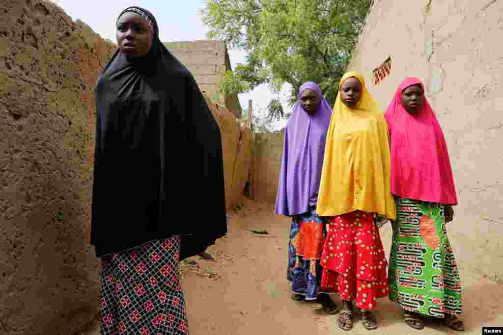 Amina Usman (L), a 15-year-old student, who was among the pupils who escaped from the attack on the school, stands with her sisters in Dapchi, the northeastern state of Yobe, Nigeria.