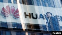 ຊາຍຄົນນຶ່ງ ຍ່າງຜ່ານຮ້ານຄ້າ ຂອງ ບໍລິສັດ ຮົວເຫວີຍ (Huawei) ໃນນະຄອນຫຼວງ ປັກກິ່ງ ຂອງຈີນ, ວັນທີ 7 ມີນາ 2019. 