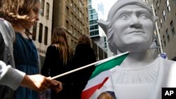 Isabella Nordstrom waves an Italian flag near a large statue of Christopher Columbus before the Columbus Day Parade in New York on Oct. 14, 2013. (AP Photo/Seth Wenig)