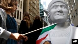 Isabella Nordstrom waves an Italian flag near a large statue of Christopher Columbus before the Columbus Day Parade in New York on Oct. 14, 2013. (AP Photo/Seth Wenig)