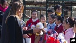 Melanija Tramp deli lutke deci u zoološkom vrtu u Pekingu 2017. (Foto: AP/Ng Han Guan)