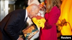 Presiden AS Joe Biden tampak menggigit kaki seorang balita dalam acara perayaan Halloween di Gedung Putih, Washington, pada 30 Oktober 2024. (Foto: Reuters/Nathan Howard)