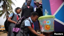 FILE - A pupil washes her hands with an improvised tap in front of a school in Nigeria.