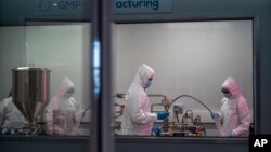 FILE - Scientists work at an Afrigen Biologics and Vaccines facility in Cape Town, South Africa, on Oct. 19, 2021. South Africa and Colombia have recently adopted a more combative approach toward drugmakers.