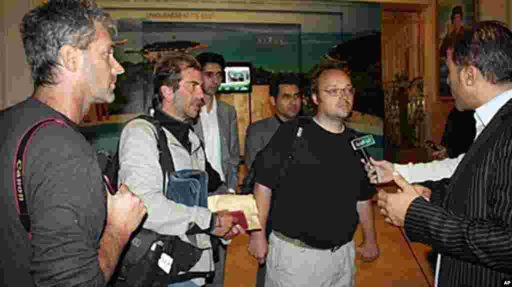 Freed journalists from Agence France Press (AFP) Roberto Schmidt (C) and Dave Clark (2nd-R) and Getty photographer Joe Raedle (L) speak to the press after their release in Tripoli, March 23, 2011