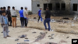 People inspect the aftermath of a suicide bombing at a soccer field in Iskandariya, 25 miles (about 40 kilometers) south of Baghdad, Iraq, March 26, 2016. 