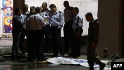 Israeli policemen stand next to the body of a suspected Palestinian attacker, who opened fire on people at a bus station in the southern Israeli city of Beersheva, Oct. 19, 2015.