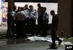 Israeli policemen stand next to the body of a suspected Palestinian attacker, who opened fire on people at a bus station in the southern Israeli city of Beersheva, Oct. 19, 2015.