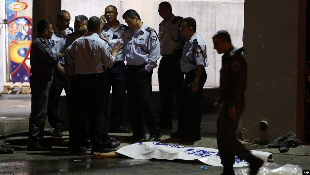 Israeli policemen stand next to the body of a suspected Palestinian attacker, who opened fire on people at a bus station in the southern Israeli city of Beersheva, Oct. 19, 2015.