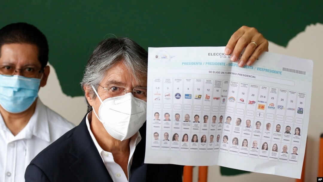 Guillermo Lasso, presidential candidate of the Creating Opportunities party or CREO, shows his ballot before voting during presidential and legislative elections, amid the new coronavirus pandemic, in Guayaquil, Ecuador, Feb. 7, 2021.
