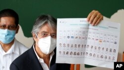 Guillermo Lasso, presidential candidate of the Creating Opportunities party or CREO, shows his ballot before voting during presidential and legislative elections, amid the new coronavirus pandemic, in Guayaquil, Ecuador, Feb. 7, 2021.