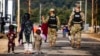 FILE - U.S. Military Police walk past Afghan refugees at the Fort McCoy U.S. Army base, Sept. 30, 2021, in Wisconsin. The fort is one of eight military installations that are temporarily housing Afghans who fled after the Taliban took over their country.