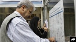 Warga Iran memeriksa daftar kandidat parlemen di sebuah TPS di Teheran, Iran (4/5). 